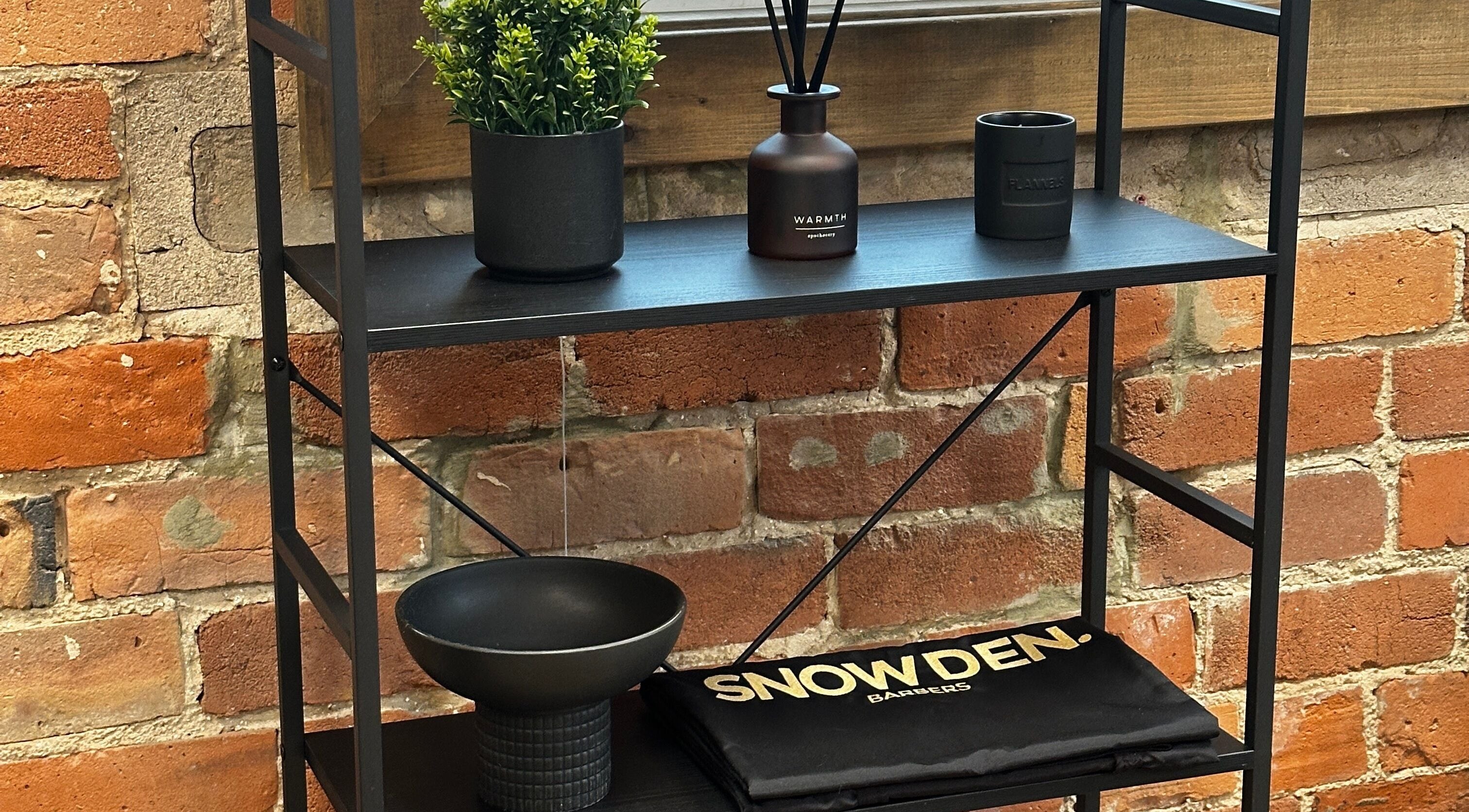 Modern black shelf at Snowden Barbers in Scunthorpe, England, GB, with plants and grooming items.