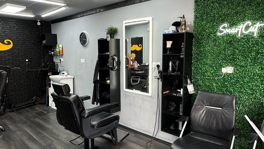 Interior of Smartcut salon in Luton, England, GB showcasing modern black chairs and green accent wall.