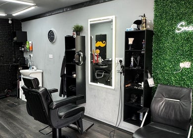 Interior of Smartcut salon in Luton, England, GB showcasing modern black chairs and green accent wall.