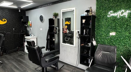 Interior of Smartcut salon in Luton, England, GB showcasing modern black chairs and green accent wall.