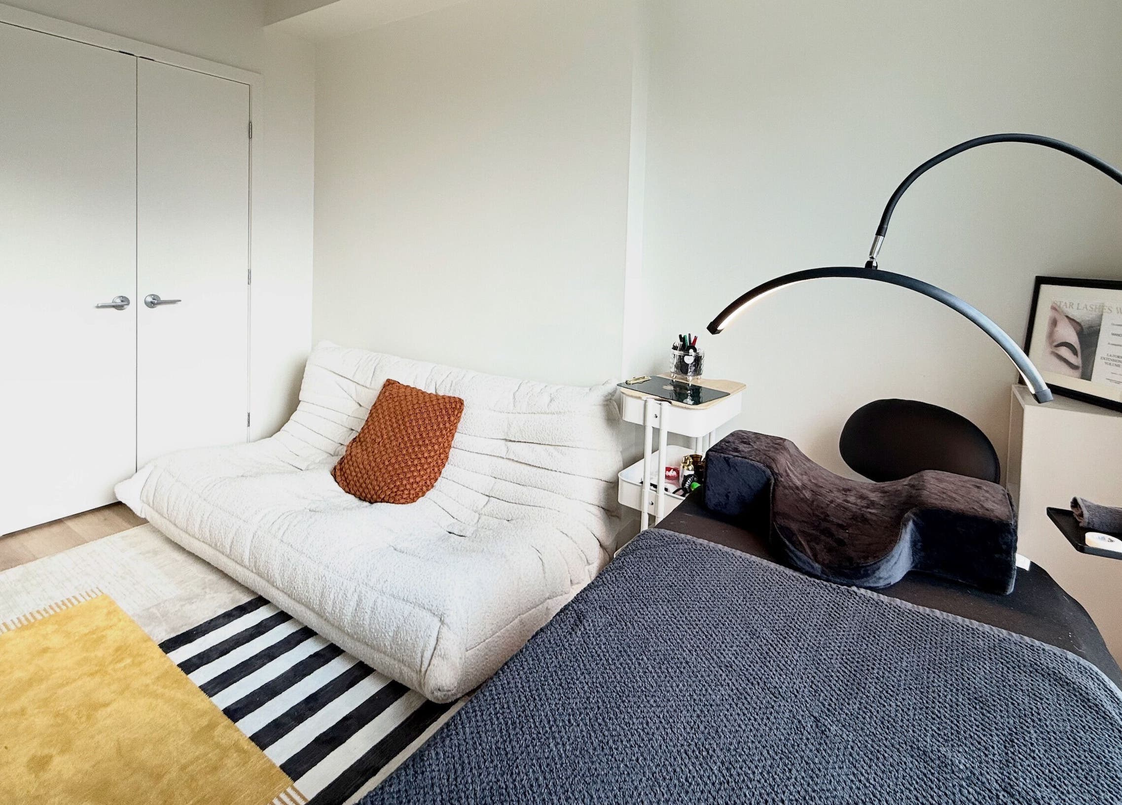 Salle de soin élégante chez La Suite 601 Beauty, Brossard, Québec, CA, avec canapé blanc et décoration moderne.