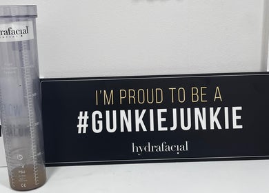 Hydrafacial sign and fluid bottle at Cosmedocs, London, England, GB showcasing '#GunkieJunkie' pride.