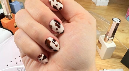 Stylish cow print manicure at Casa De La Kasey, Moyock, North Carolina, US with nail polish in background.