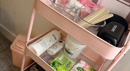 Beauty supplies on pink cart at Daisy's Laser Hair Removal, Par, England, GB, showcasing tools and skincare items.