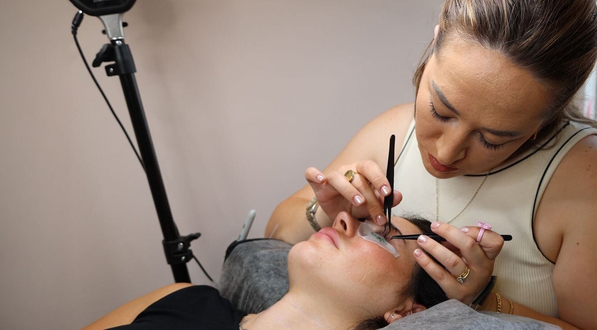 Lash artist at Lashes_byirsi in London, England, GB applying extensions with tweezers.