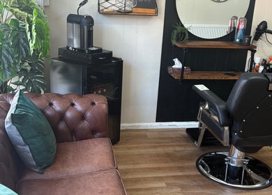 Cozy salon interior at Cuts by Amy with brown leather couch and styling chair in Earls Colne, England, GB.