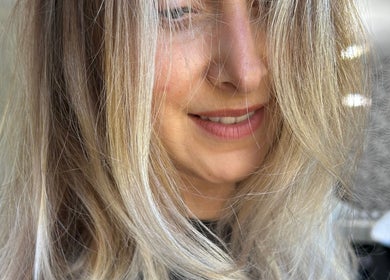 Stylish blonde hair at Rachael @seventysix, Dunmow, England, GB salon. Soft waves complement a bright smile.