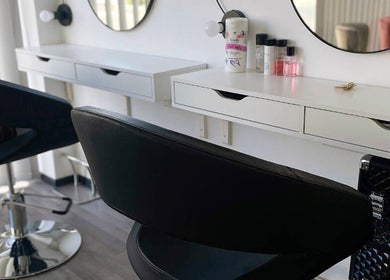 Modern salon station at HEY BEAUTY, Lemesos, CY with mirrors, black chairs, and beauty products.