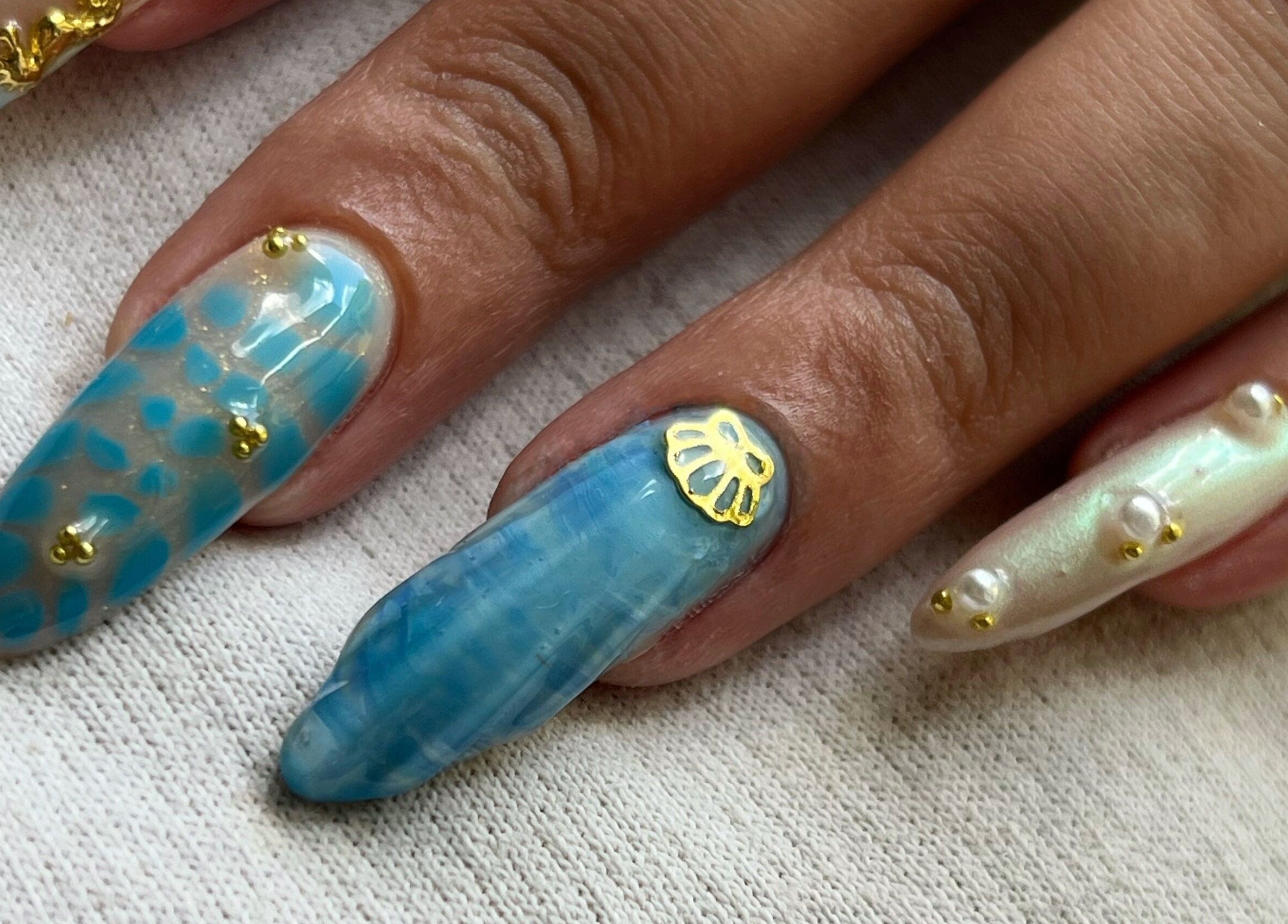 Manucure élégante chez Nailsbynahia à Pau, Nouvelle-Aquitaine, FR avec motifs marins et accents dorés.