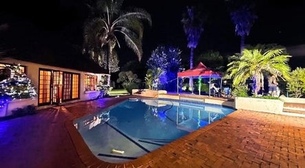Omar Beauty Spa's poolside patio at night in Chartwell, Gauteng, ZA, featuring lit tropical gardens and tranquil ambiance.