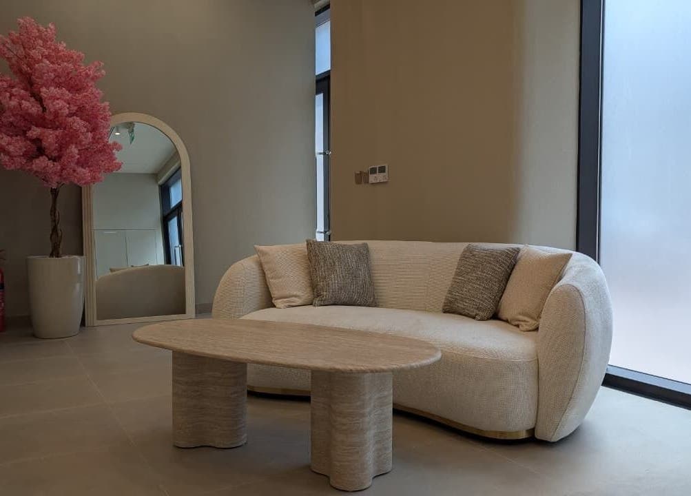 Elegant lounge at Sheboss Timeless Beauty Saloon LLC, Dubai, AE, featuring a plush sofa and pink blossom decor.