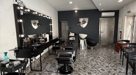 Interior moderno da Barbearia Santana em Maia, Porto, PT, com cadeiras elegantes e espelho iluminado.