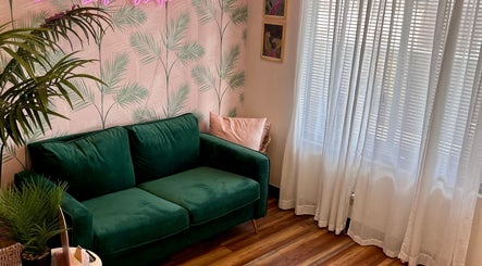 Chic green sofa in The Luxe Lash Studio, Dana Point, California enhances cozy atmosphere with elegant decor.