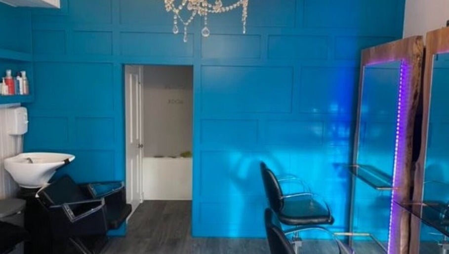 Stylish salon interior at Hair By Natasha in Edinburgh, Scotland, GB with vibrant blue walls and modern chairs.