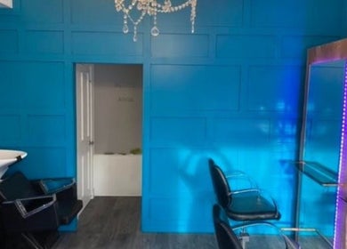 Stylish salon interior at Hair By Natasha in Edinburgh, Scotland, GB with vibrant blue walls and modern chairs.