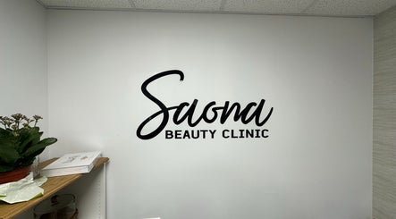 Saona Beauty Clinic wall logo in Pembroke Pines, Florida, US with a plant and books on a shelf nearby.