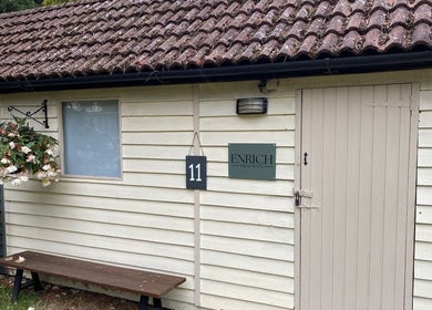 Rustic exterior of Enrich Treatments in Saffron Walden, England with floral display and signage.