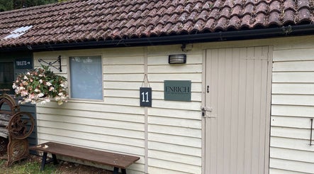 Rustic exterior of Enrich Treatments in Saffron Walden, England with floral display and signage.