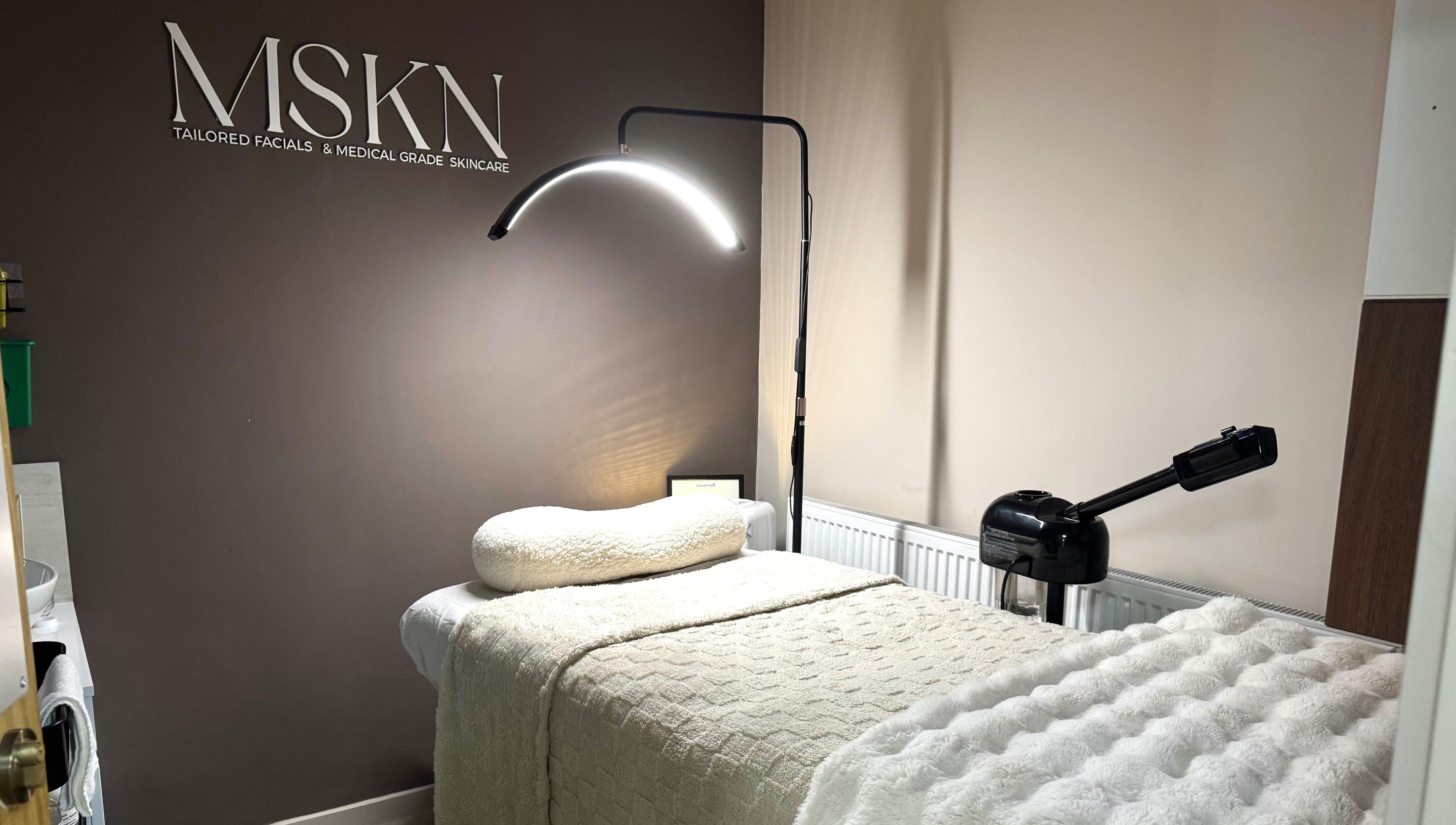 Cozy skincare treatment room at MSKN, Manchester, England, GB with plush bed and modern lighting.