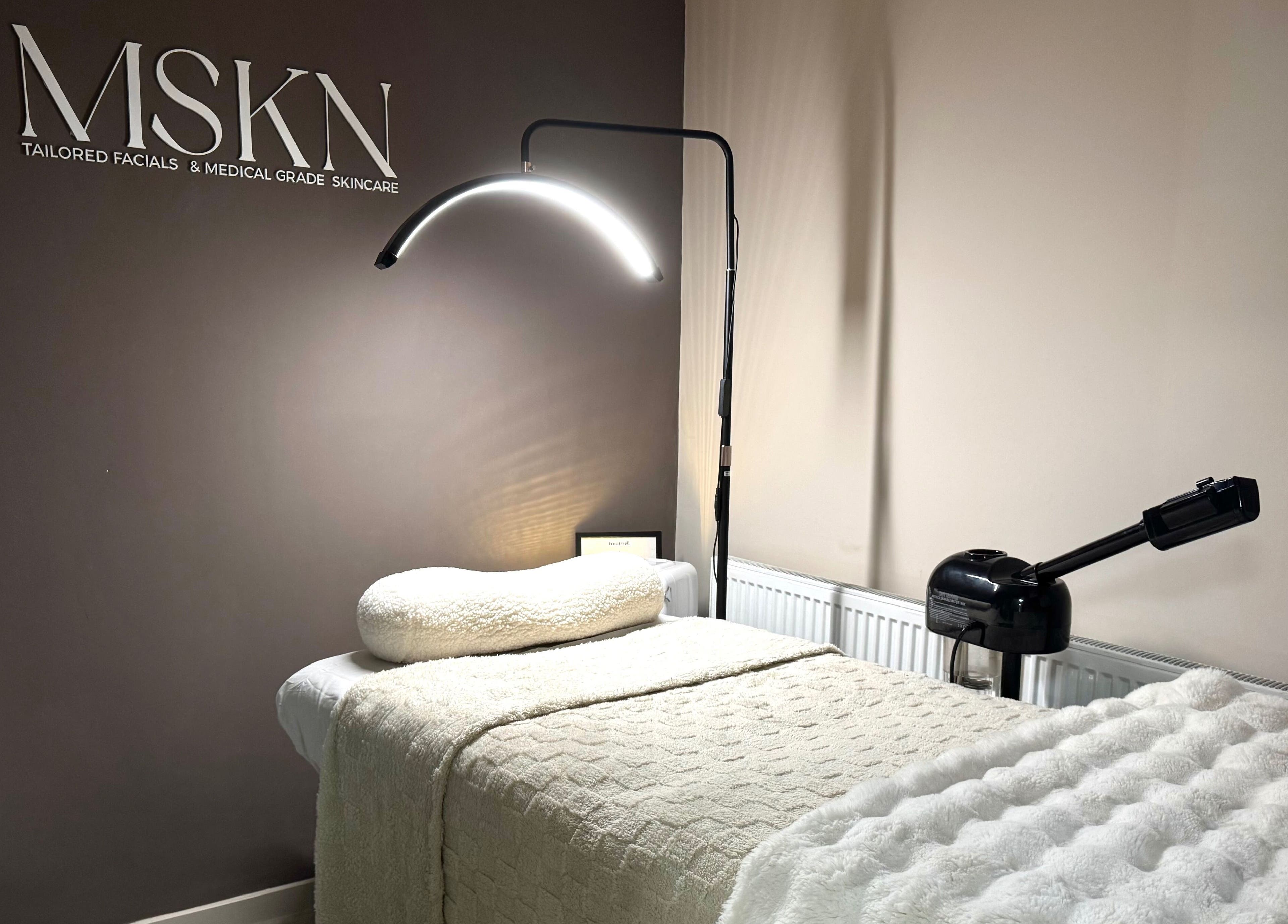 Cozy skincare treatment room at MSKN, Manchester, England, GB with plush bed and modern lighting.