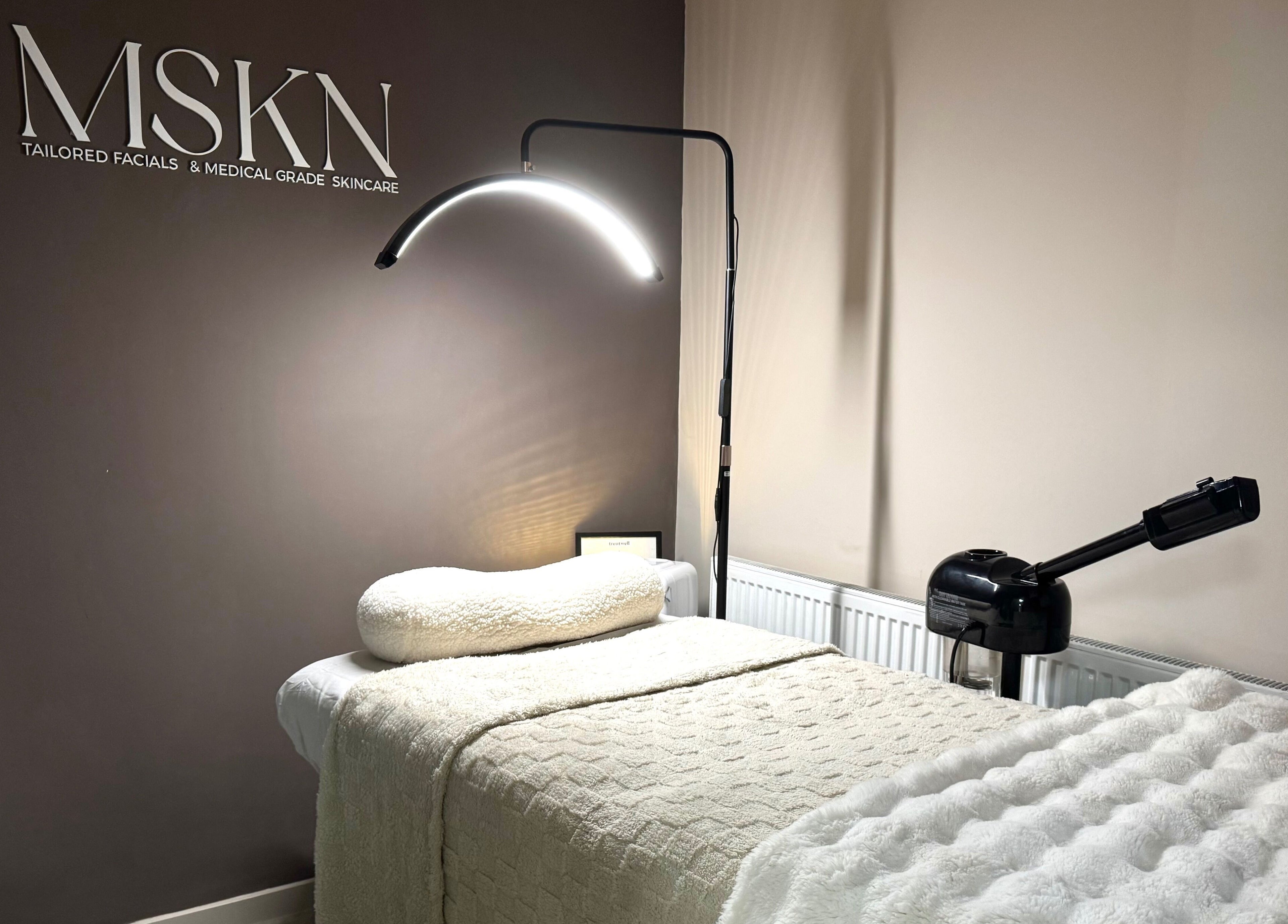 Cozy skincare treatment room at MSKN, Manchester, England, GB with plush bed and modern lighting.