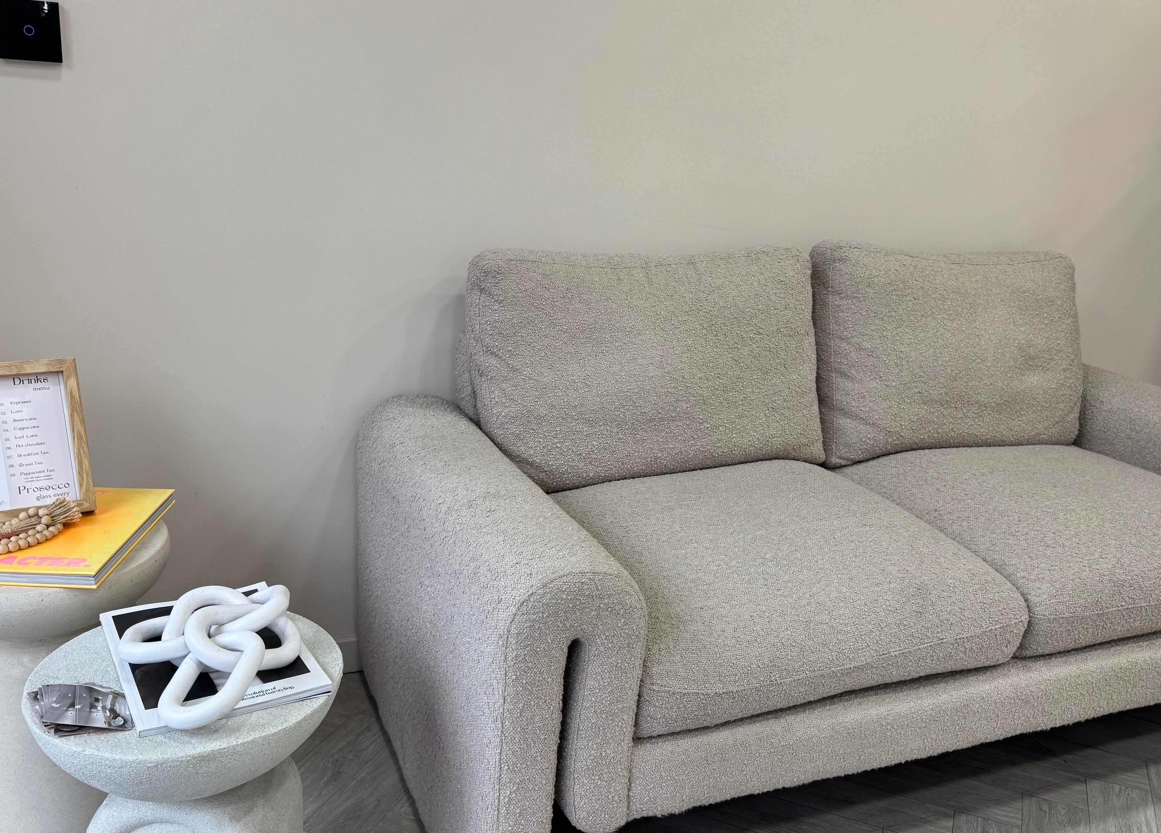 Elegant gray sofa at MSKN, Manchester, England, GB, with decor and drinks menu on the side.