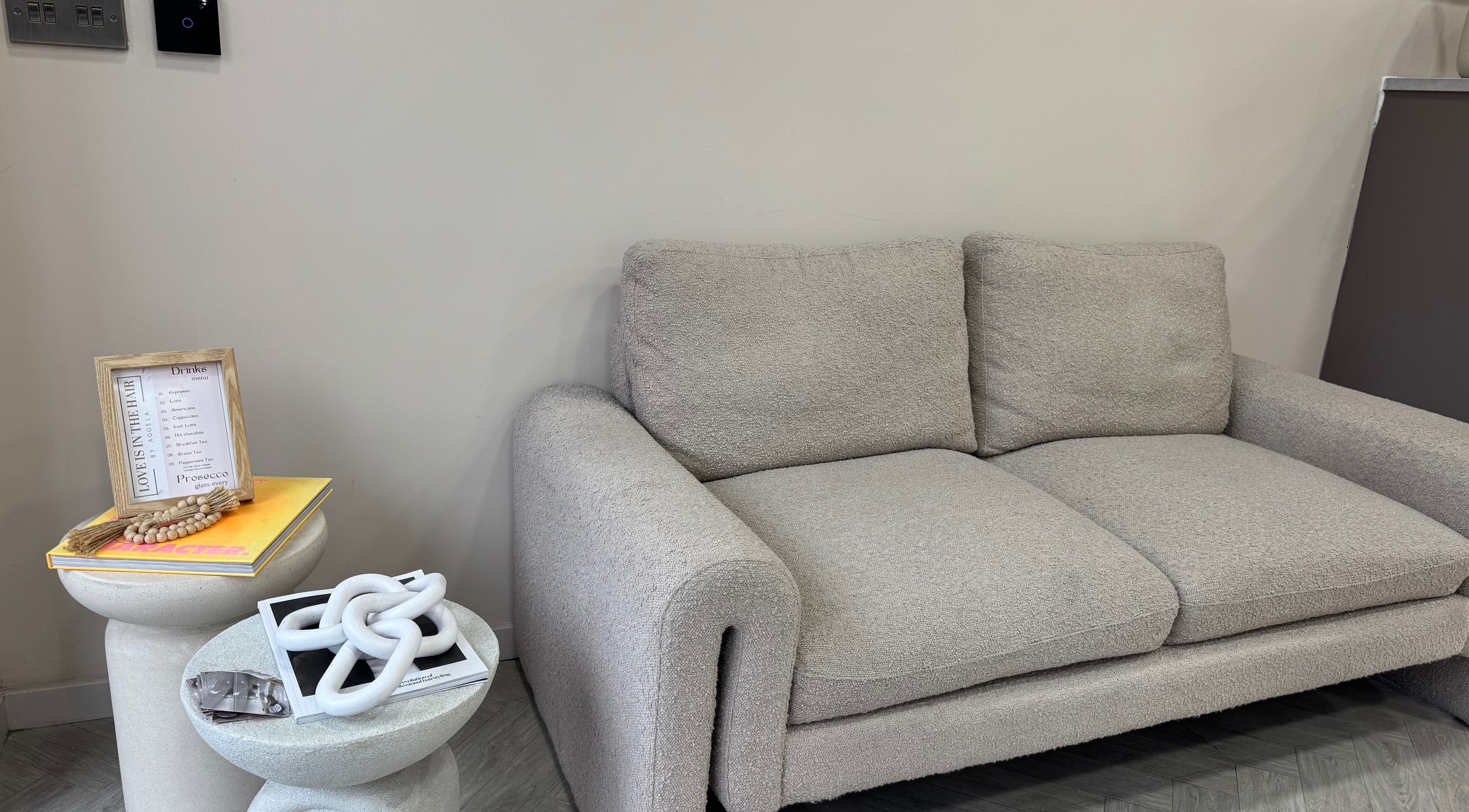 Elegant gray sofa at MSKN, Manchester, England, GB, with decor and drinks menu on the side.