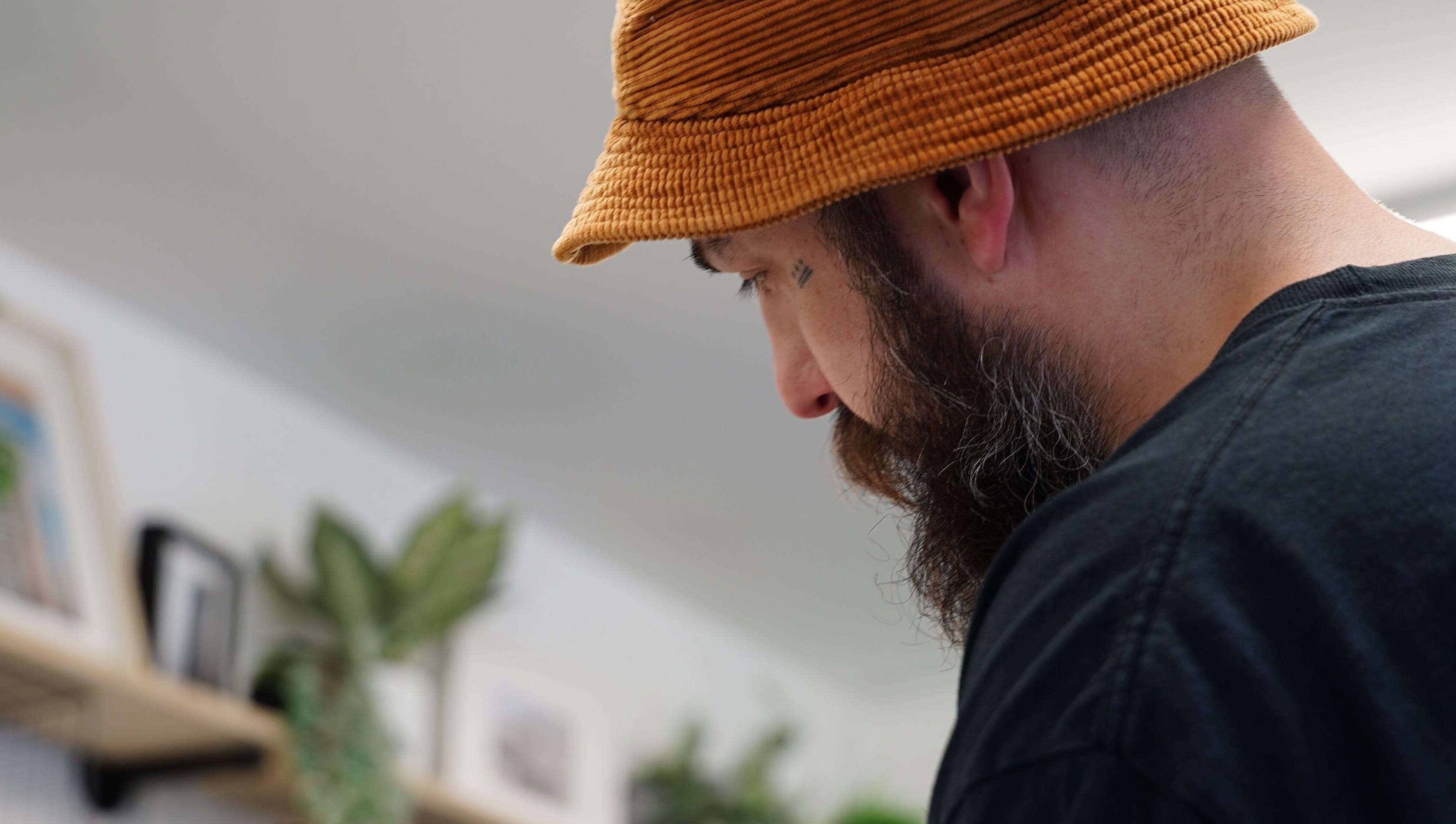 Barber working at Jay @ ATP Soho, London, England, GB, in a modern setting with green plants.