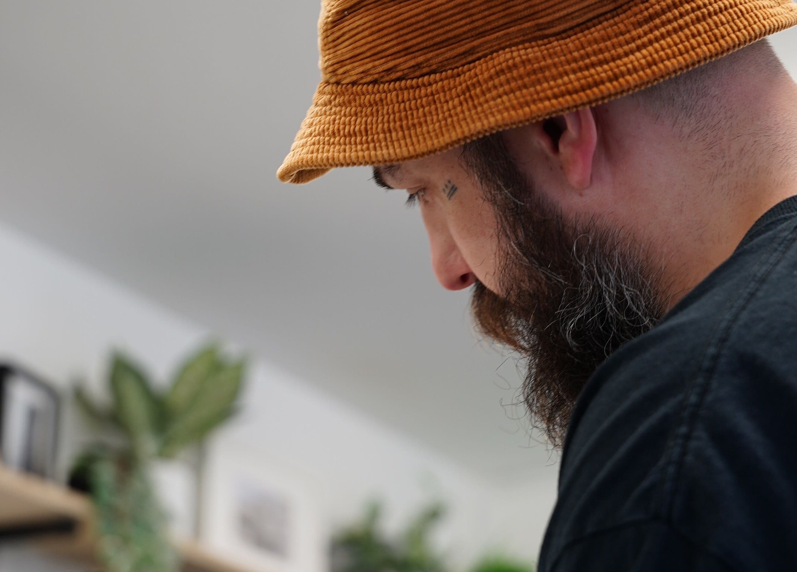 Barber working at Jay @ ATP Soho, London, England, GB, in a modern setting with green plants.