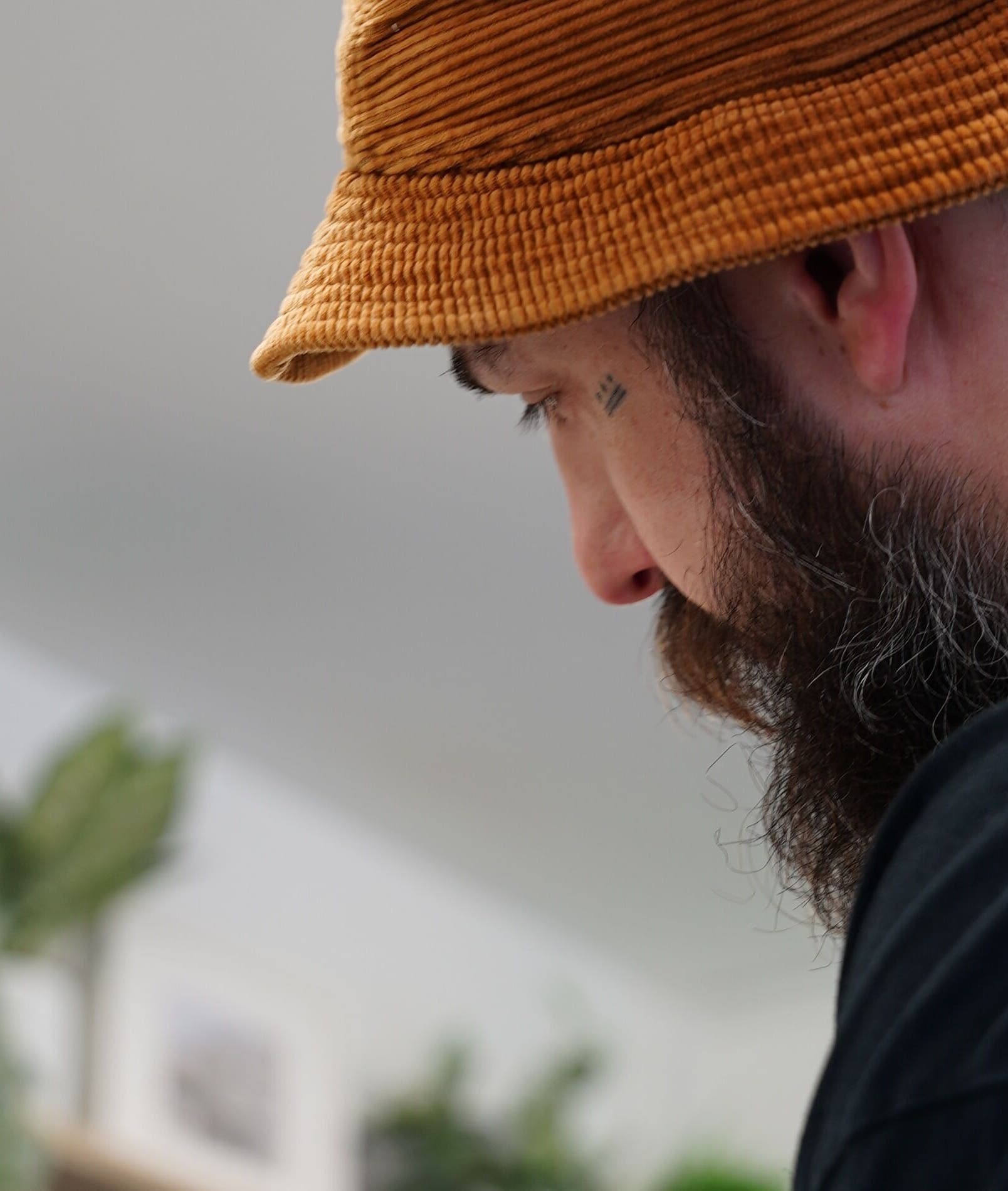 Barber working at Jay @ ATP Soho, London, England, GB, in a modern setting with green plants.