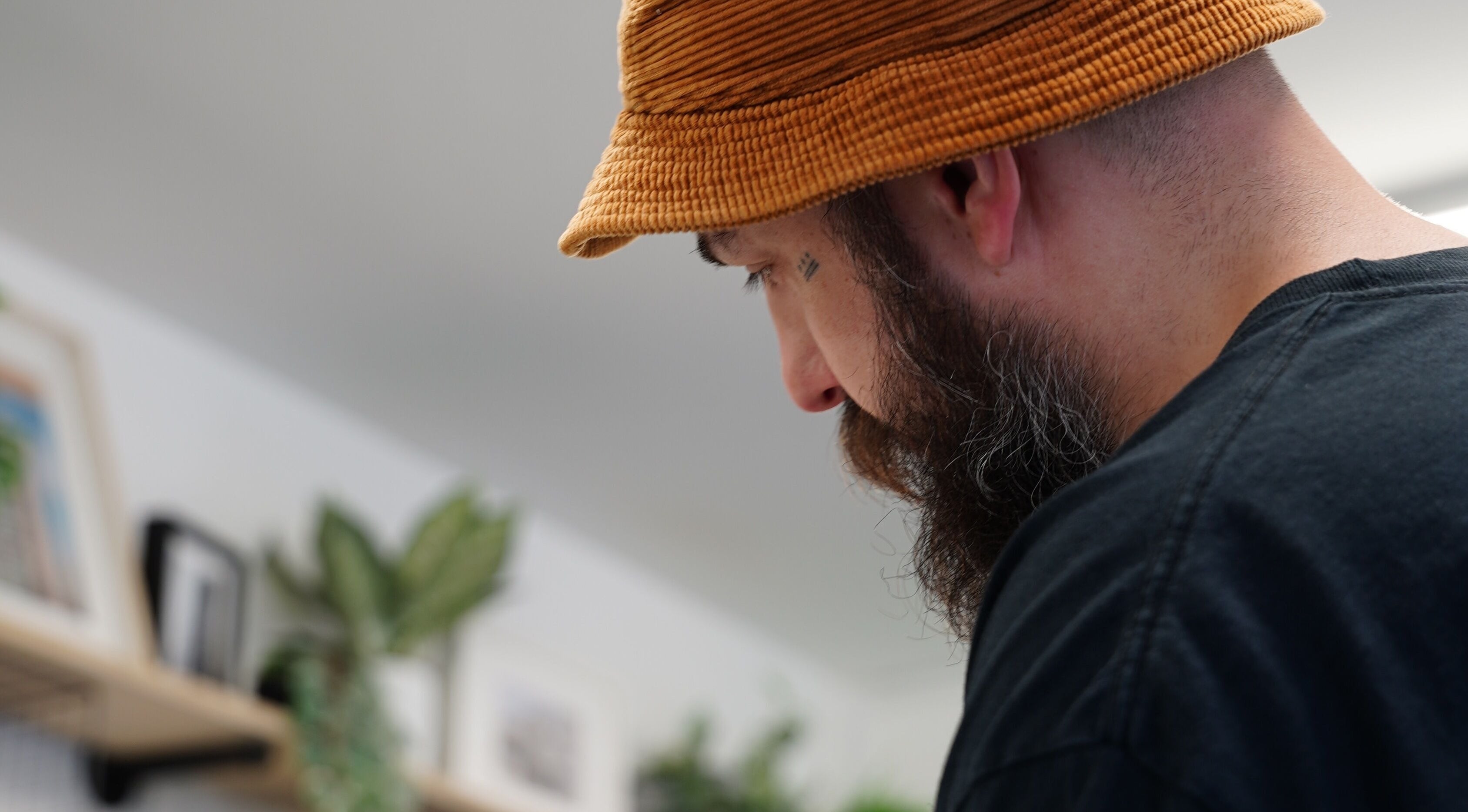 Barber working at Jay @ ATP Soho, London, England, GB, in a modern setting with green plants.