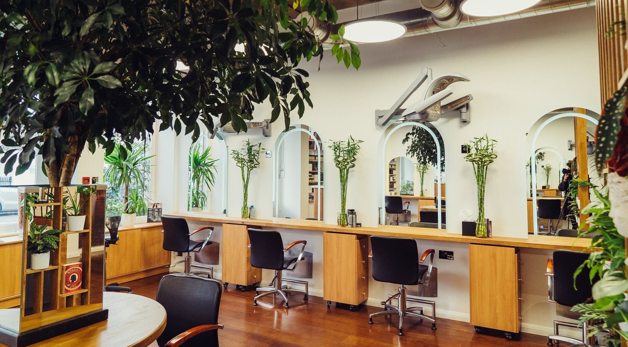 Bright, elegant salon chairs and mirrors at ADEM, London, England, GB, surrounded by lush greenery.
