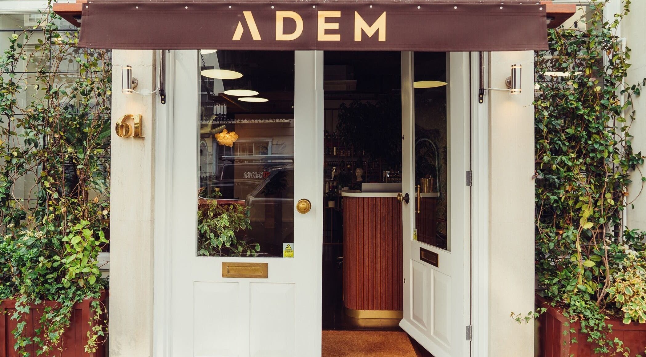 Entrance to ADEM salon with elegant door and green vine decor, located in London, England, GB.