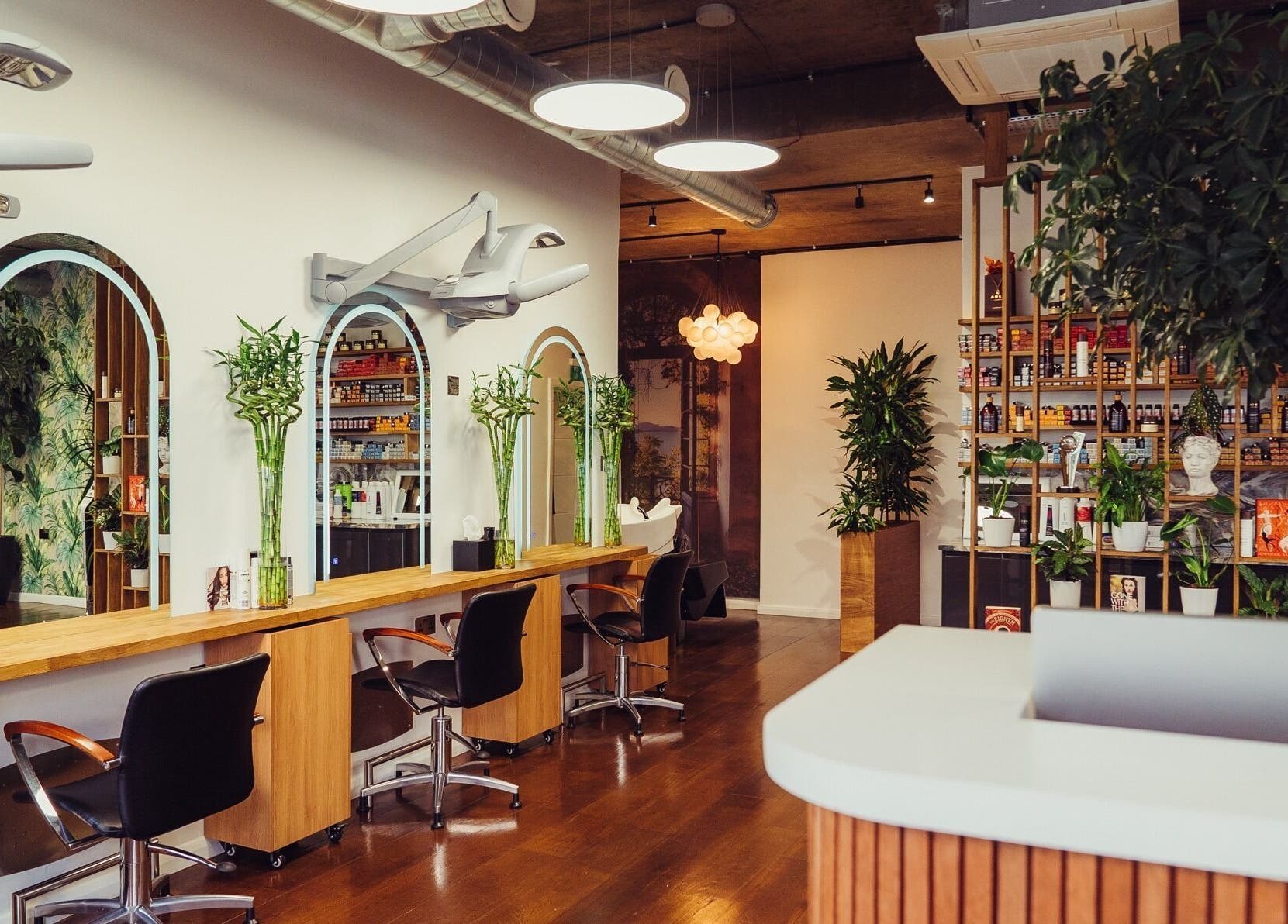 Modern salon interior at ADEM in London, England, GB featuring stylish stations and lush greenery.
