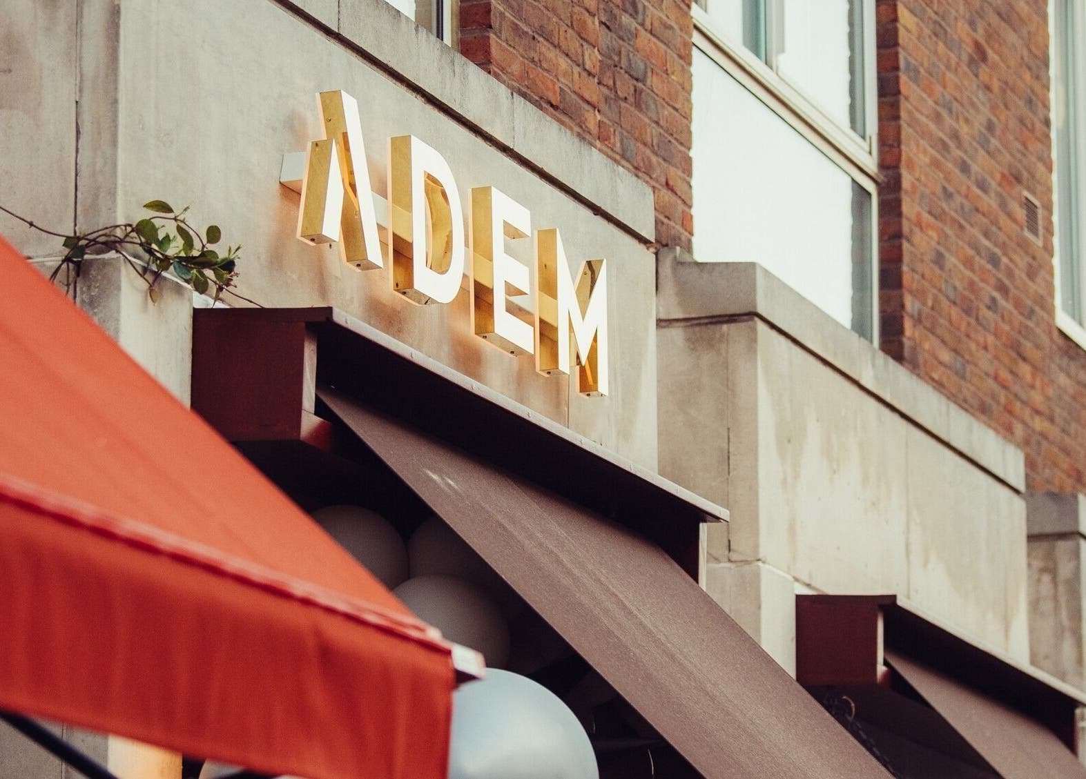 ADEM venue facade in London, England, GB with golden signage and red awning.