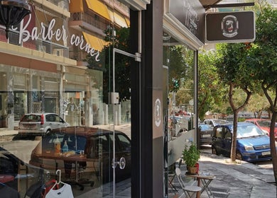 Η είσοδος του Barber Corner στην οδό Βύρωνας, GR, με σήμανση και δέντρα μπροστά.