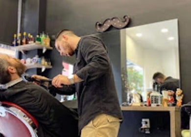 Μάστορας μαλλιών στο Barber Corner, Βύρωνας, GR οργανώνει γενειάδα πελάτη με προσοχή.