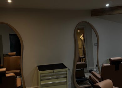 Chic interior of Reset Barbers in Beccles, England, GB, featuring stylish salon chairs and wavy mirrors.