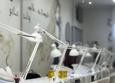 Маникюрная станция в Sadoo Ladies Beauty Center в Абу-Даби, AE, со стильными лампами и местами для клиентов.