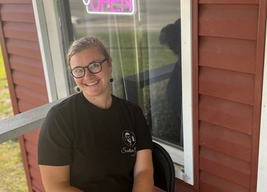 Smiling individual at Southern Gents entrance in Swainsboro, Georgia, US, with an open neon sign visible.