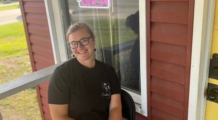 Smiling individual at Southern Gents entrance in Swainsboro, Georgia, US, with an open neon sign visible.