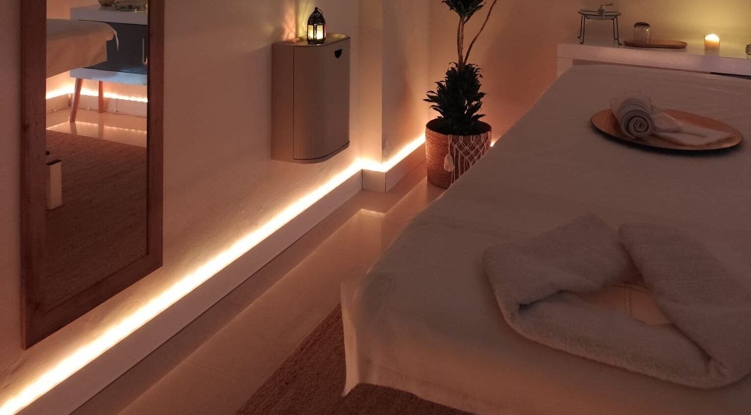 Sala de masaje Ámbar Masajes, València, Comunidad Valenciana, ES, con iluminación suave y toallas blancas.