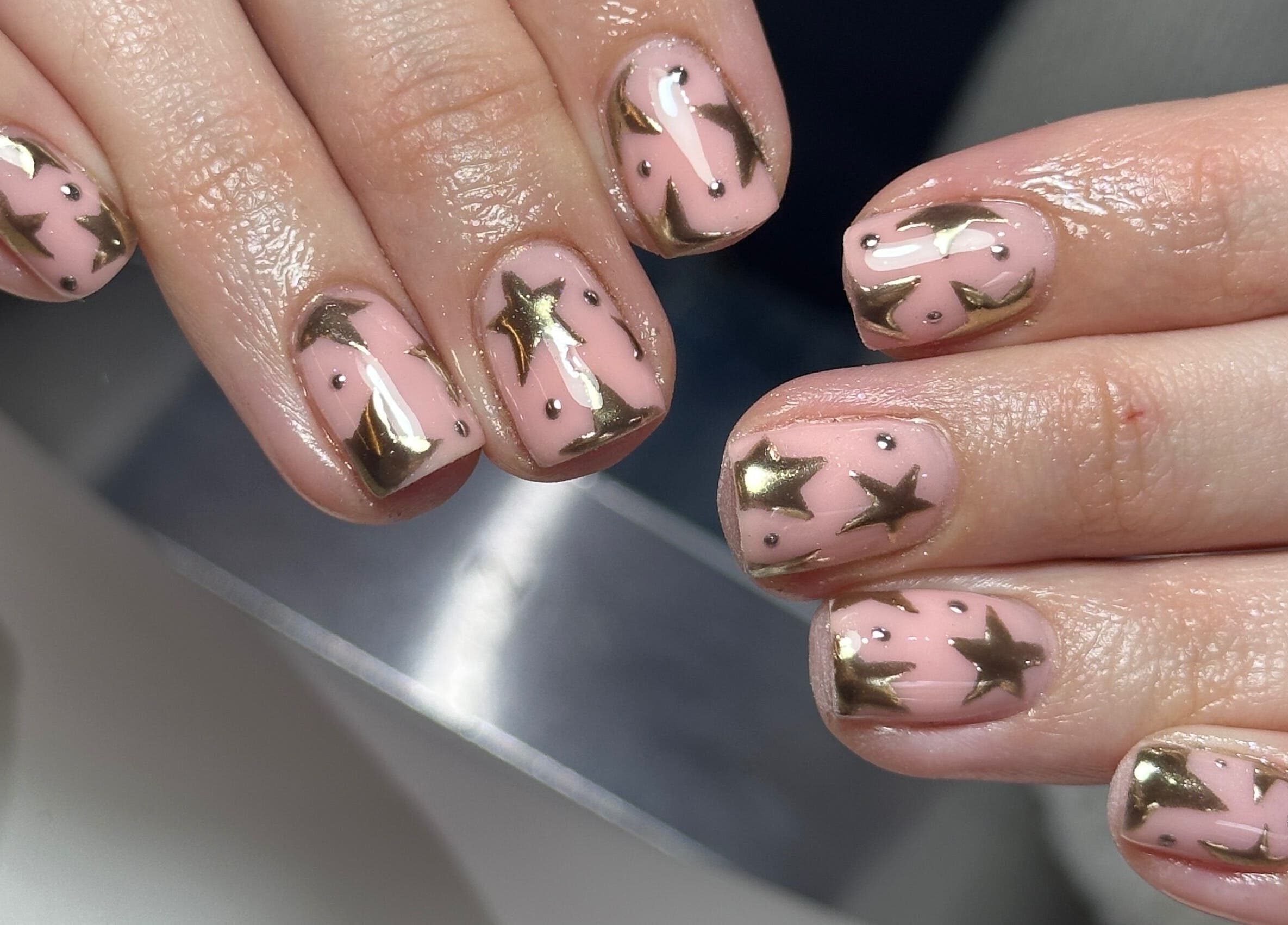 Elegant star nail art by Nails By Kay in Bromsgrove, England, GB. Gold stars on pink background.