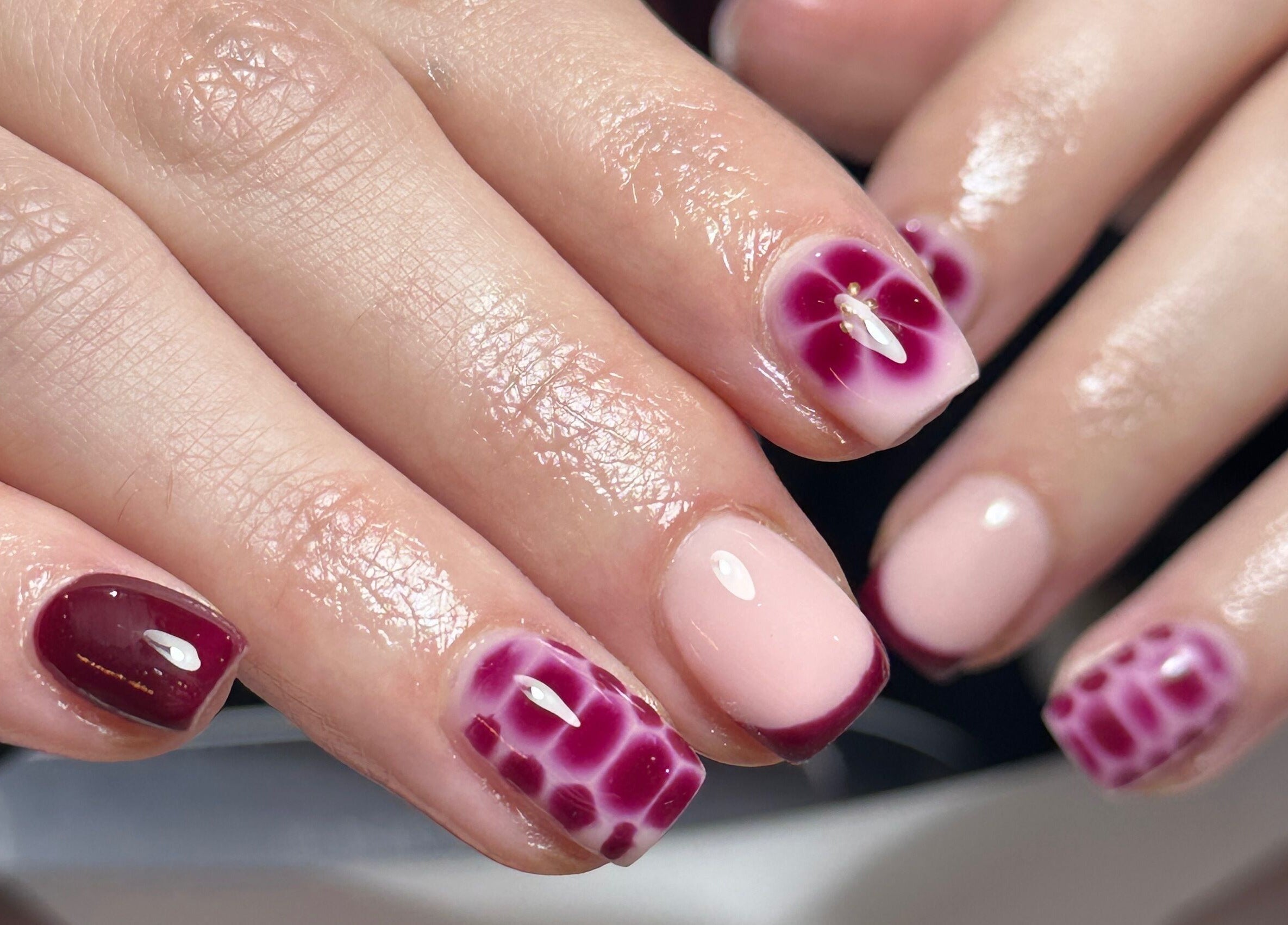Intricate nail art at Nails By Kay, Bromsgrove, England, GB, featuring maroon and pink designs.