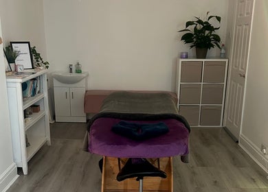 Relaxing spa room at Rooted Therapies by Vic in Whiston, England, GB, featuring a massage table and calming decor.
