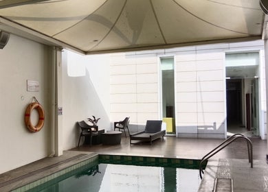 Relaxing poolside view at Ojas Wellness Spa, Bengaluru, Karnataka, IN. Featuring lounge chairs and a serene ambiance.