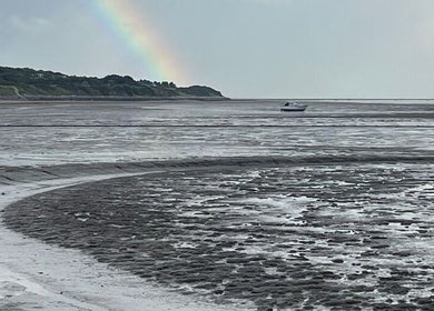 Peaceful beach scene near GC Therapies, Liverpool, England, GB with a rainbow in the sky.