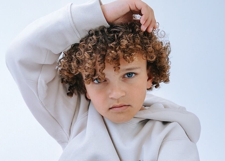 Kind met krullend haar in lichtblauwe achtergrond bij JZ works, Zoetermeer, Zuid-Holland, NL.