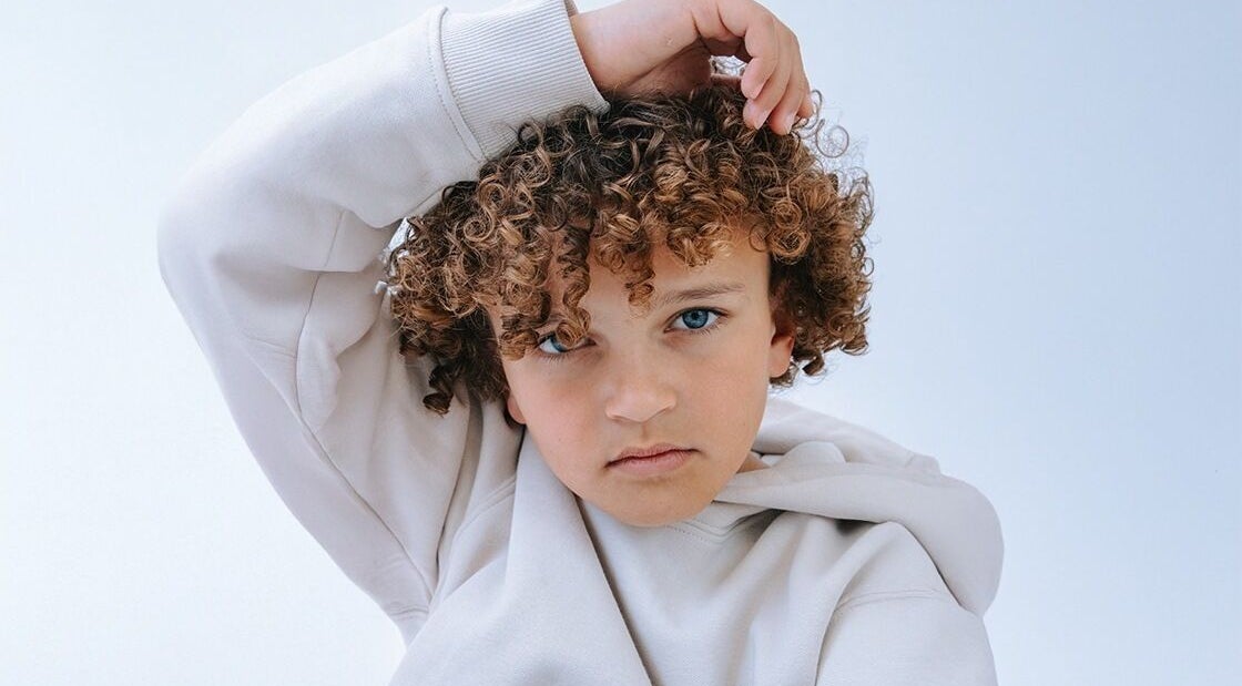 Kind met krullend haar in lichtblauwe achtergrond bij JZ works, Zoetermeer, Zuid-Holland, NL.