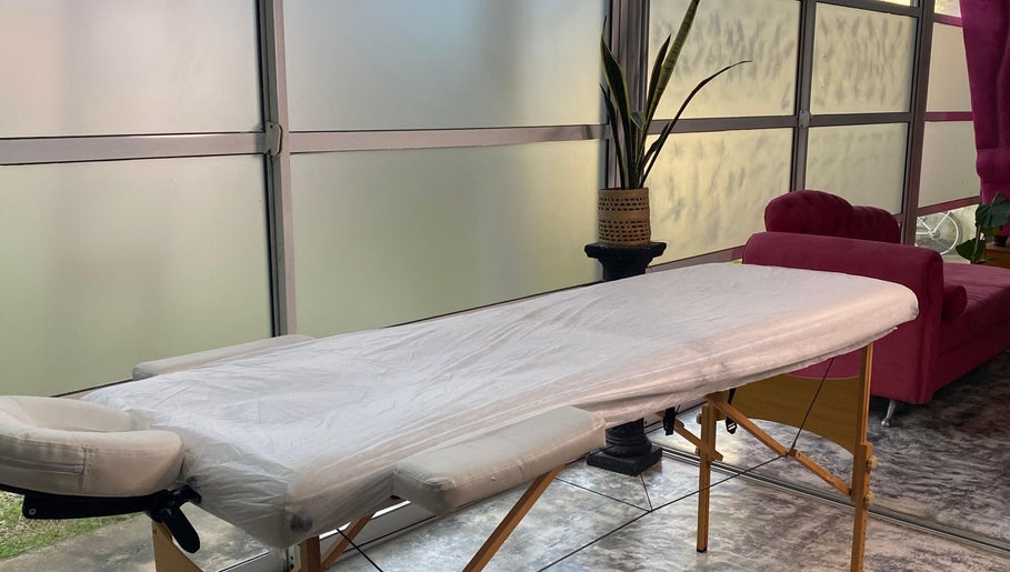 Sala de tratamiento en Lashes Club, Concordia, Entre Ríos, AR. Camilla cómoda junto a sofá y planta decorativa.